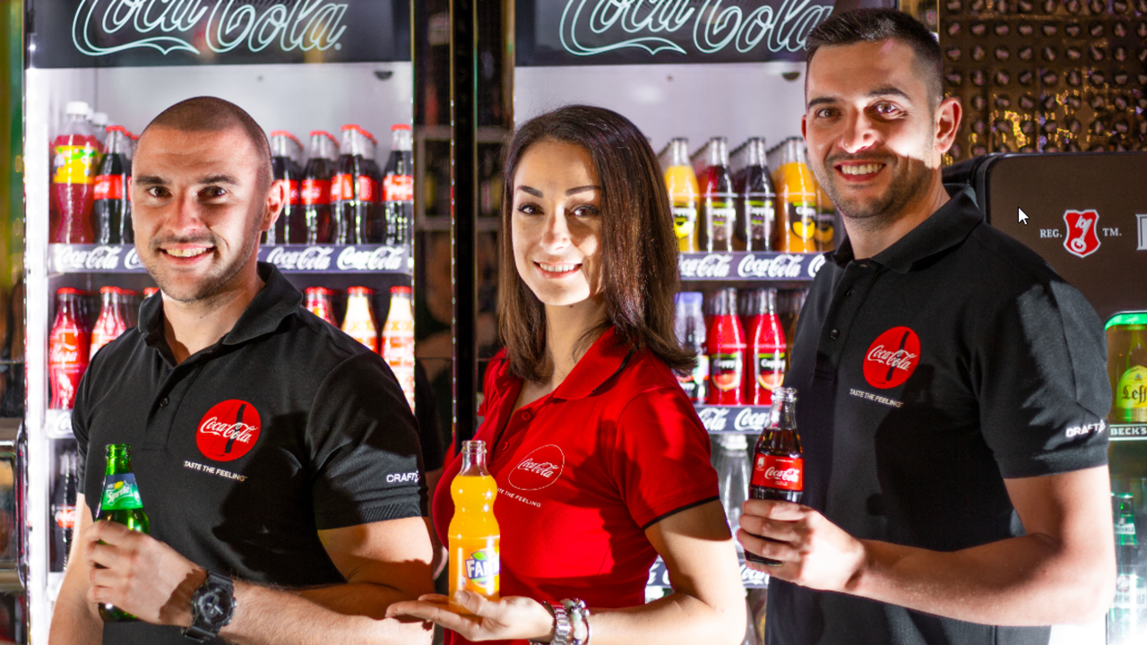 troje ljudi stoji sa Coca-Colinim proizvodima